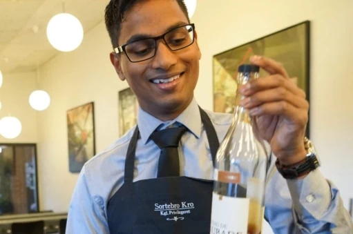 Elev på tjeneruddannelsen fortæller om vinen til maden, hvilket er en del af undervisningen