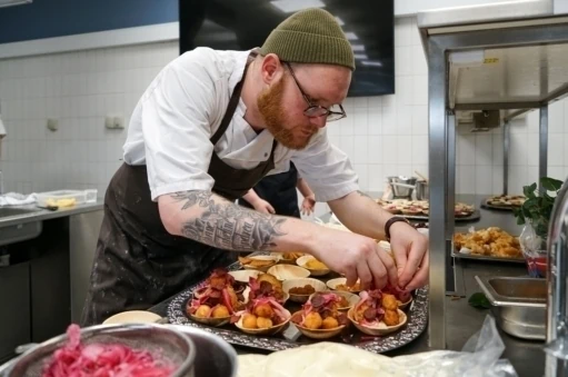 Underviser på kokkeuddannelsen hjælper til i køkkenet sammen med eleverne