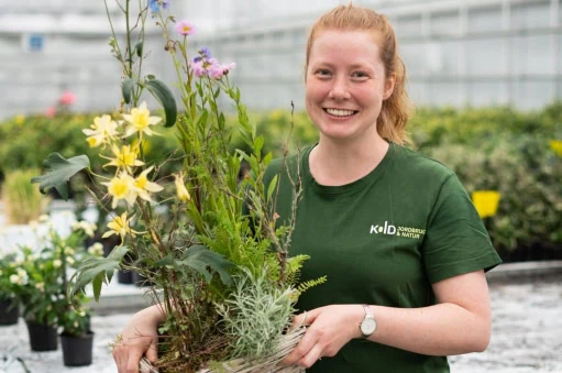 Elev på gartner uddannelse der står midt i skolen drivhus fuld af blomster og planter